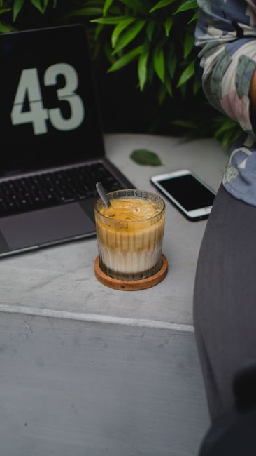 Tác Dụng Phụ Của Macca Úc Khi Ăn Quá Nhiều Cần Lưu Ý 5 A relaxing coffee break with a latte, laptop, and smartphone in a tranquil cafe setting.