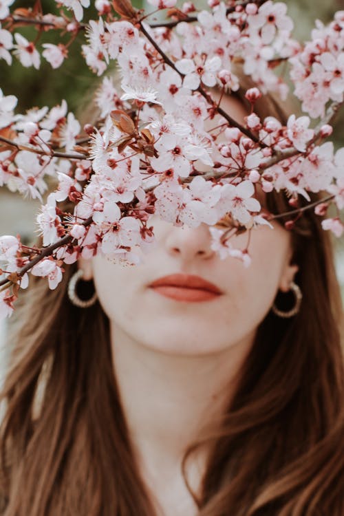 Young Brunette Standing Behind Blossoming Branches