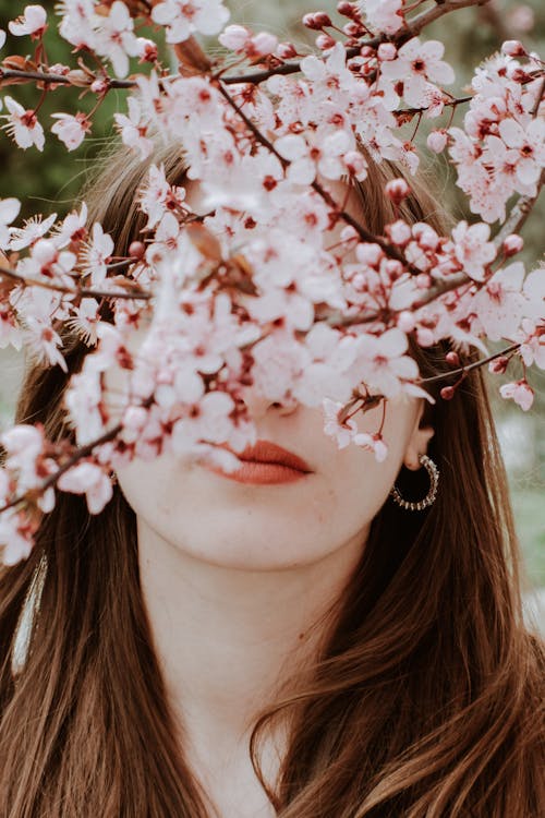 Woman Standing behind Blooming Cherry Branch