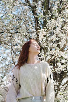 A serene portrait of a woman amidst blossoming trees during spring in Гродно, Беларусь.