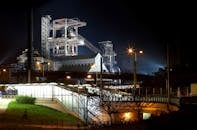 一座工业工厂灯火通明，钢结构在夜空中闪闪发光