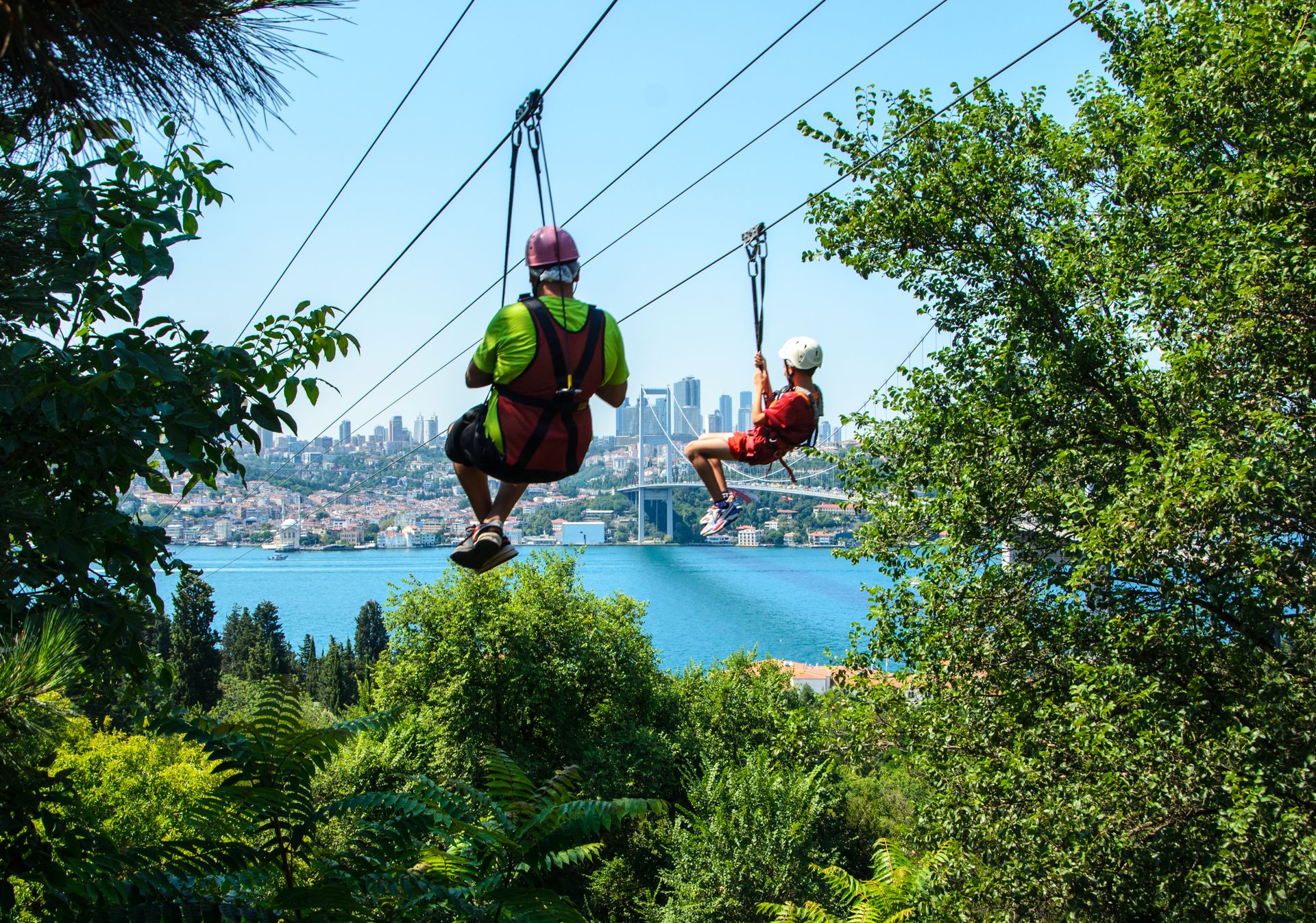 Thrilling ziplining experience overlooking a bustling cityscape, surrounded by lush vegetation.