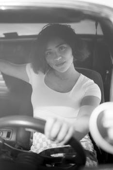 Black and white portrait of a woman sitting in a vintage car, Los Angeles.