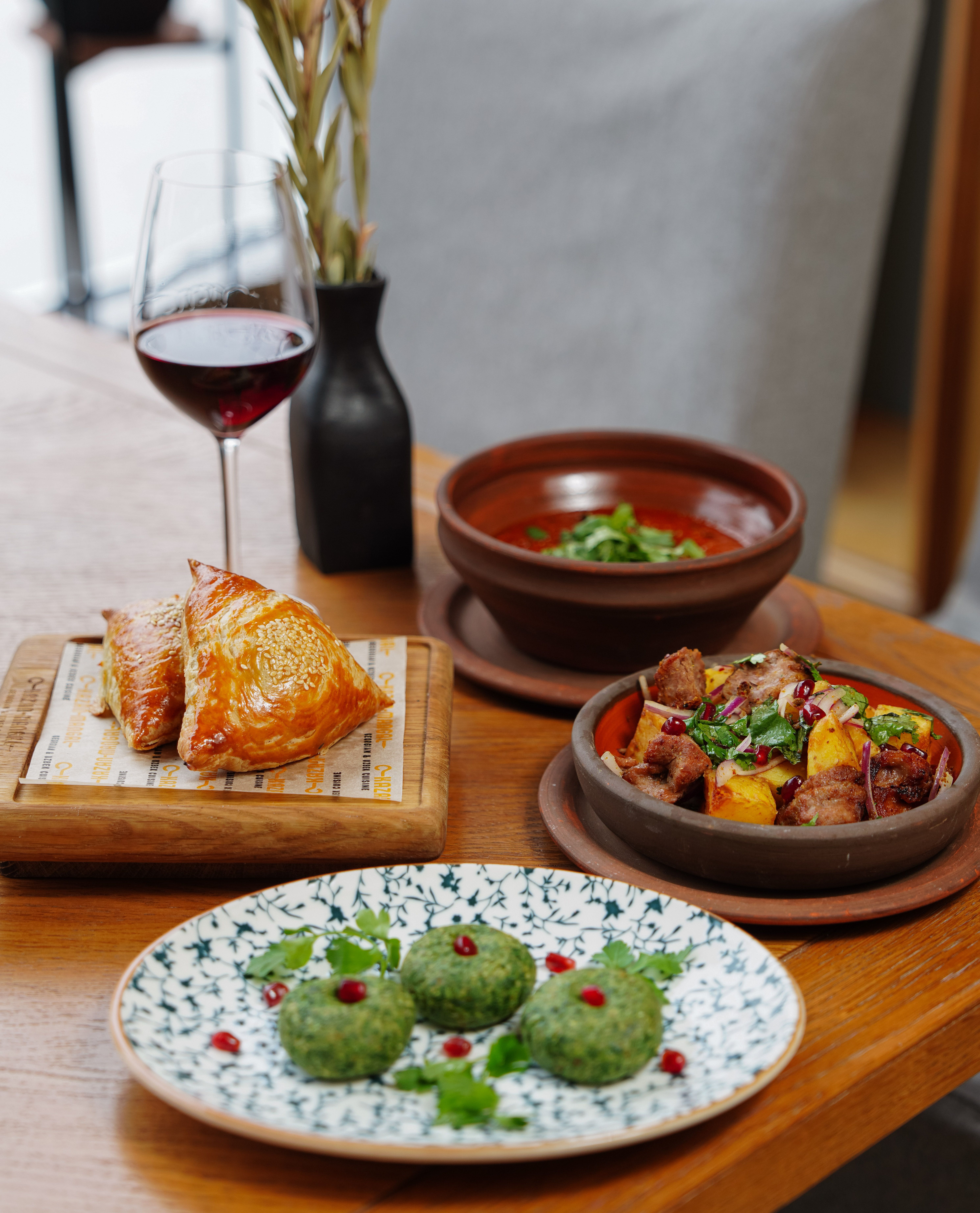 A delectable array of Mediterranean cuisine with a glass of red wine on a wooden table.