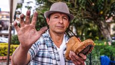 A shoemaker in Chordeleg, Ecuador, proudly exhibits his craft and tools outdoors.