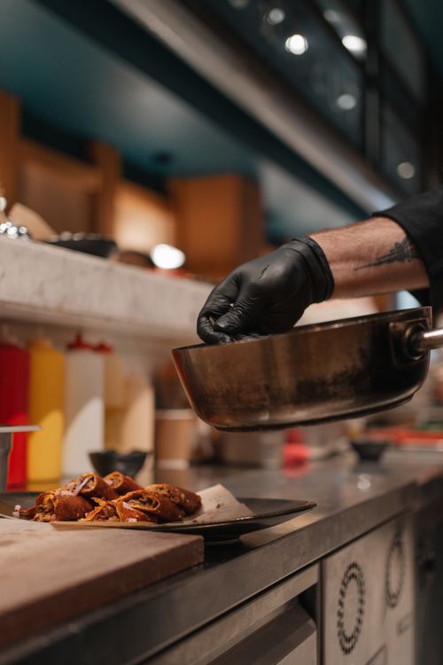 Free Chef wearing black gloves plates a gourmet dish in a modern Istanbul kitchen. Stock Photo