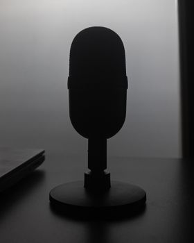Elegant silhouette of a microphone on a table with a soft backlight.