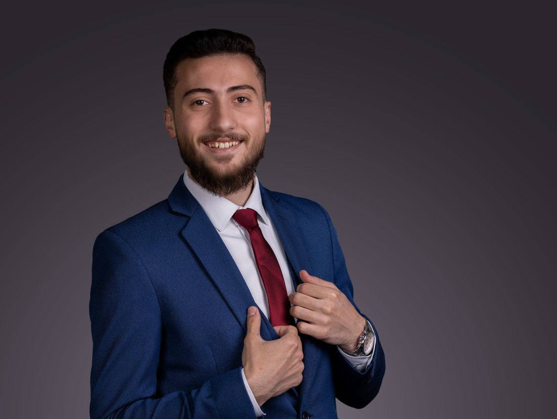 Confident young businessman in a blue suit and red tie, smiling with elegance
