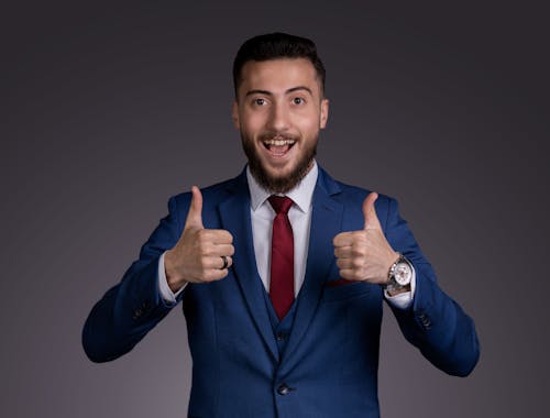 Smiling Man in Suit Standing with Thumbs Up