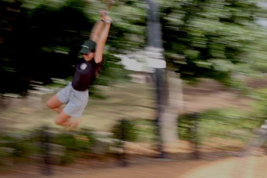 Blurred motion image of a person enjoying a thrilling zipline ride in a lush outdoor setting.