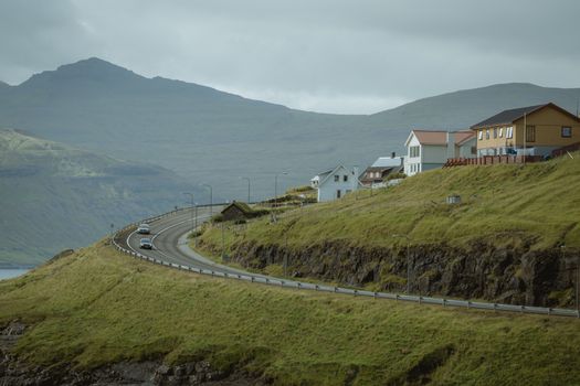 A winding road passes through a picturesque village set against mountain views.