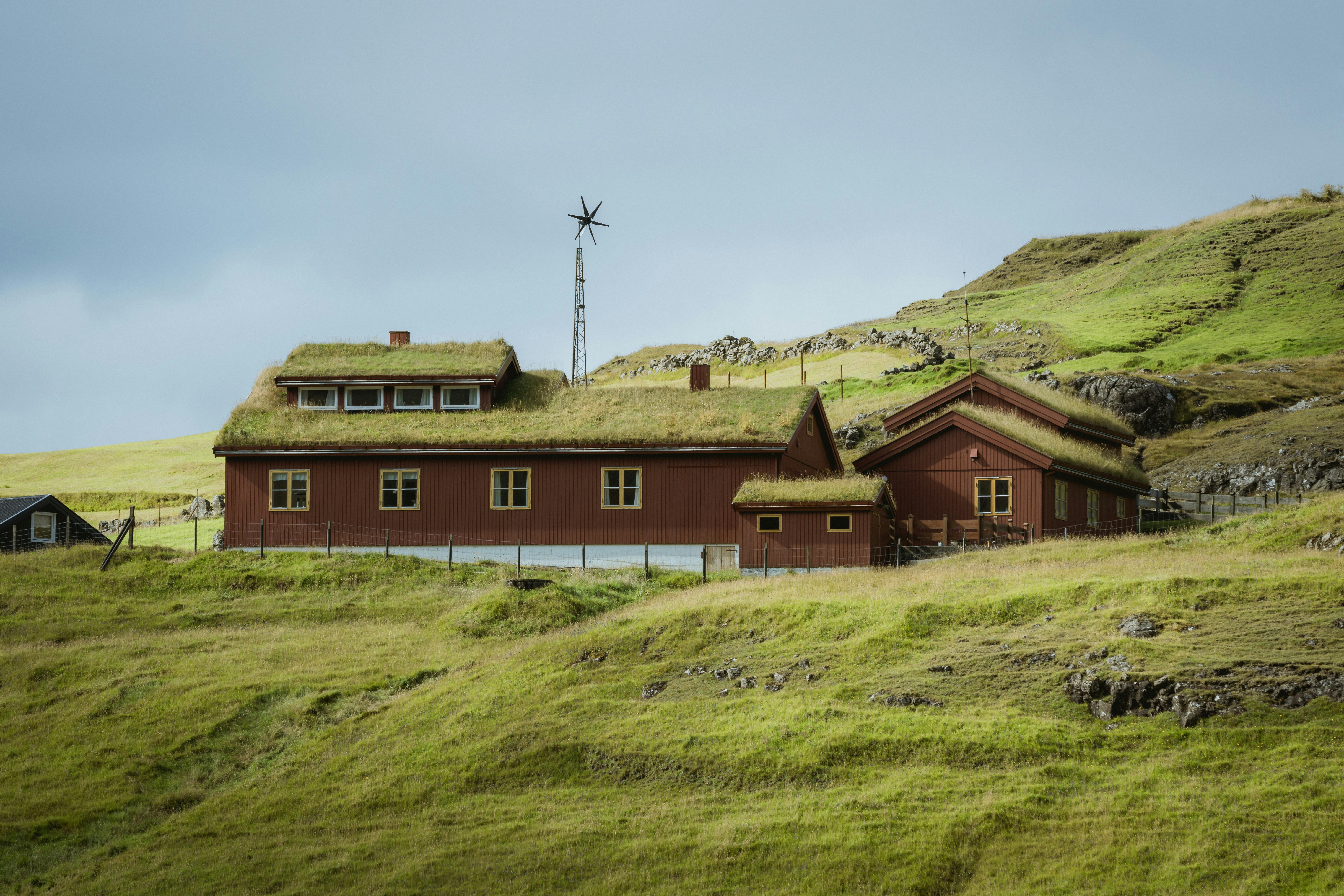 Free Rustic sod-roof houses in the rolling hills of the Faroe Islands, showcasing traditional architecture. Stock Photo