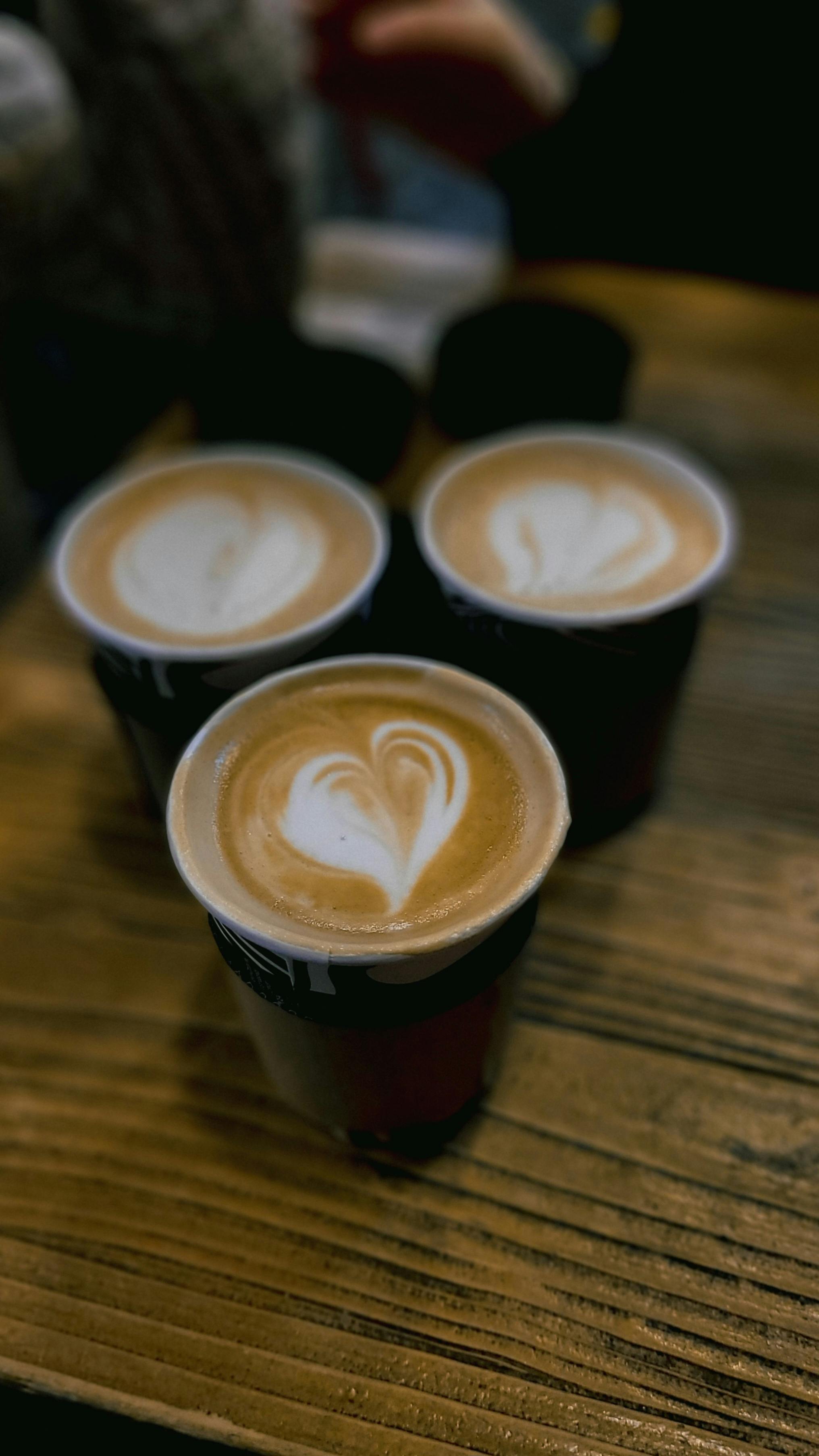 Hand Sprinkling A Cappuccino On A Cafe Table · Free Stock Photo