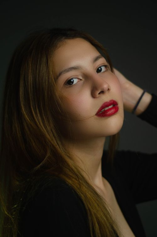 Free Chic portrait of a woman with red lipstick on a dark studio background. Stock Photo