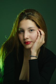 Studio portrait of a young woman with red lips and green lighting, exuding elegance and beauty.