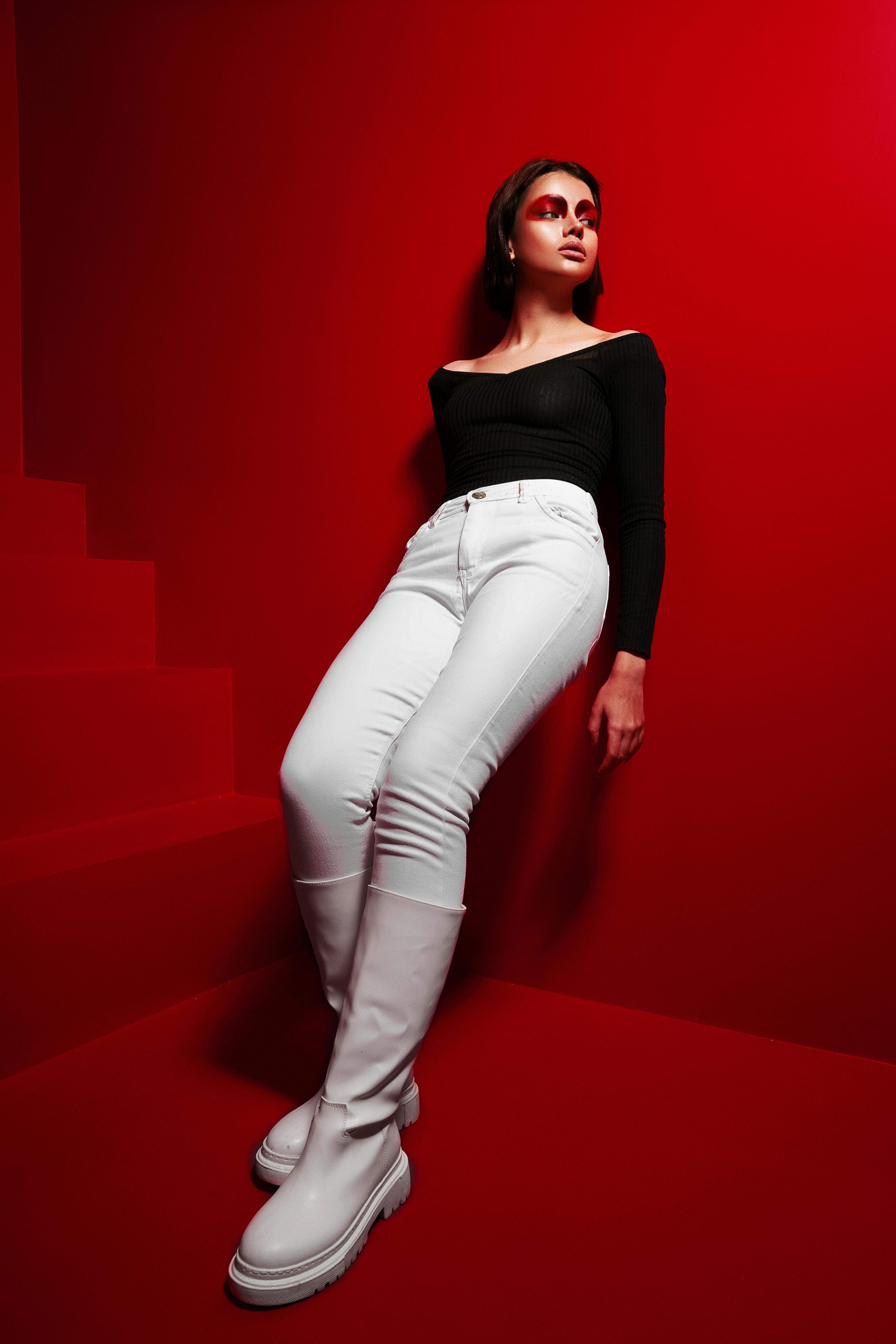 Fashionable woman posing against a striking red background, creating a bold visual statement.