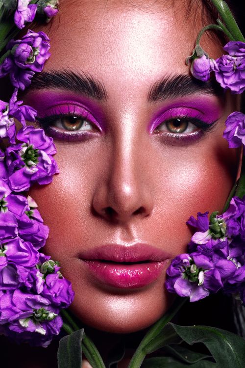 Free Stunning portrait featuring vibrant purple makeup and floral accents, highlighting beauty and elegance. Stock Photo