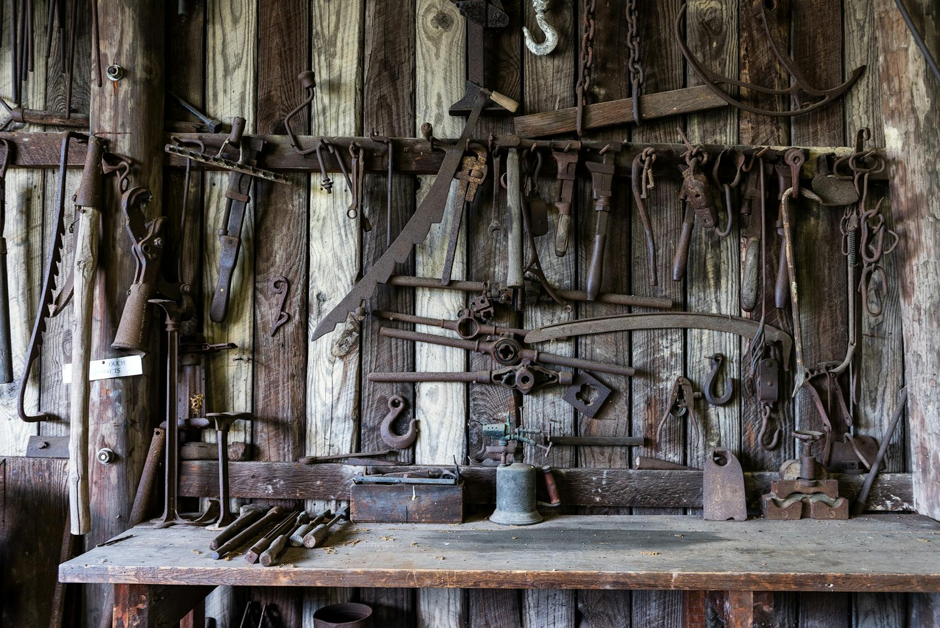 Rustic wood-paneled workshop showcasing vintage, rusty tools. Perfect for themes of heritage and craftsmanship.