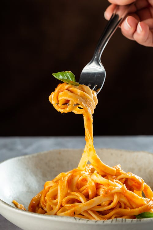Close-up of Woman Holding a Fork over the Pasta Dish 