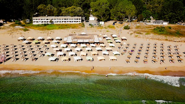 Aerial view of a beach resort with sun loungers and umbrellas, perfect for a summer vacation.