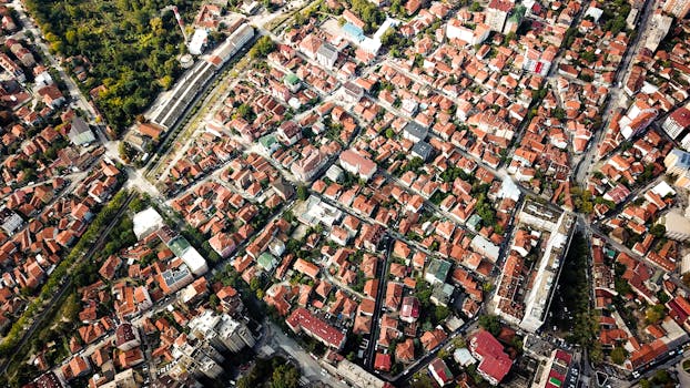 Aerial shot showcasing city blocks with distinct red-roofed buildings and greenery.