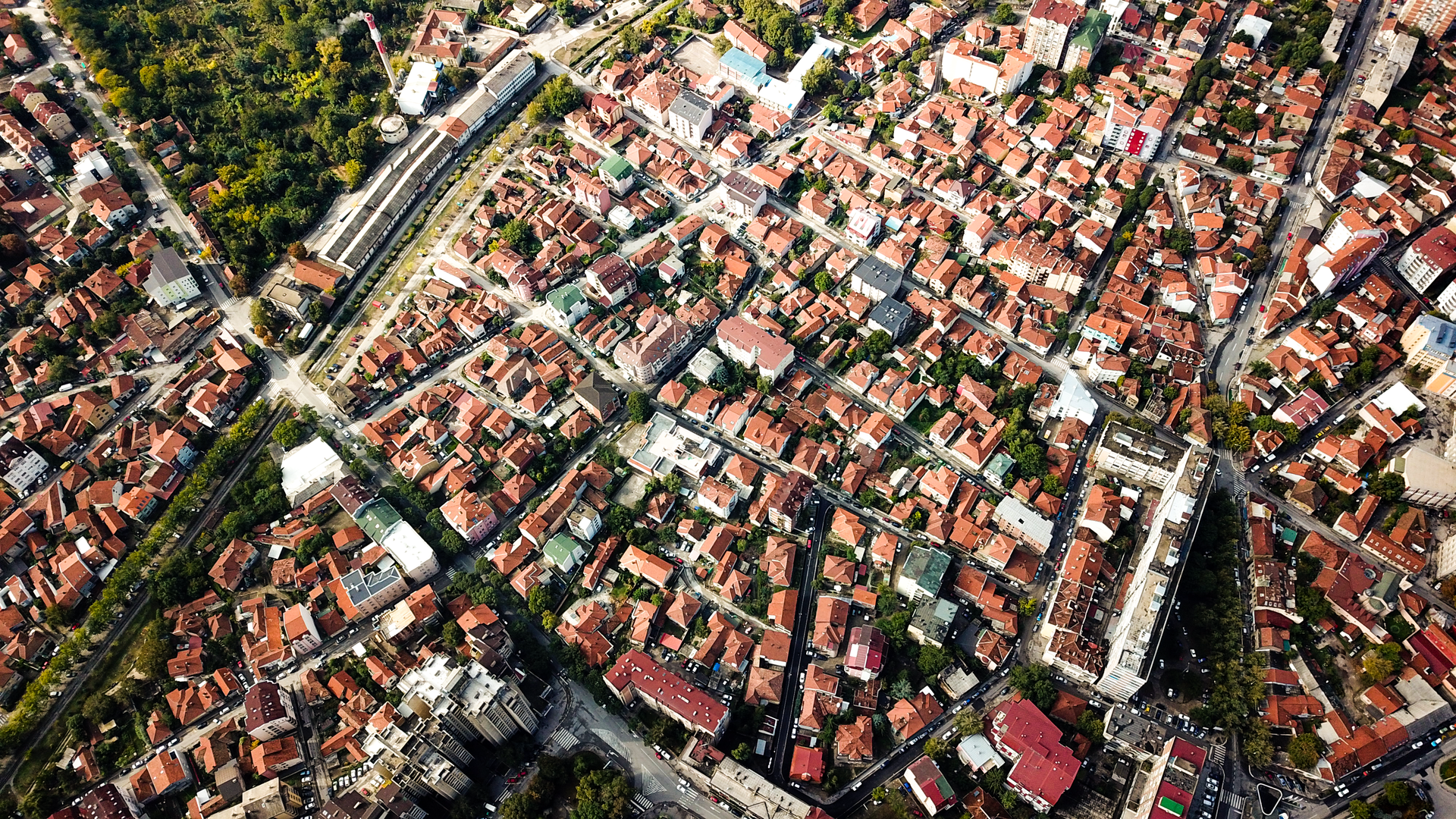 Aerial shot showcasing city blocks with distinct red-roofed buildings and greenery.