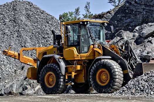 Powerful yellow construction loader moving gravel in an industrial quarry site.