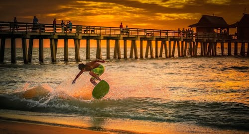 Man Wearing Green Shorts Surfing during Golden Hour