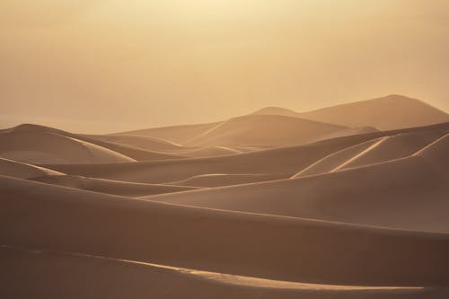 The sun is setting over the desert with sand dunes