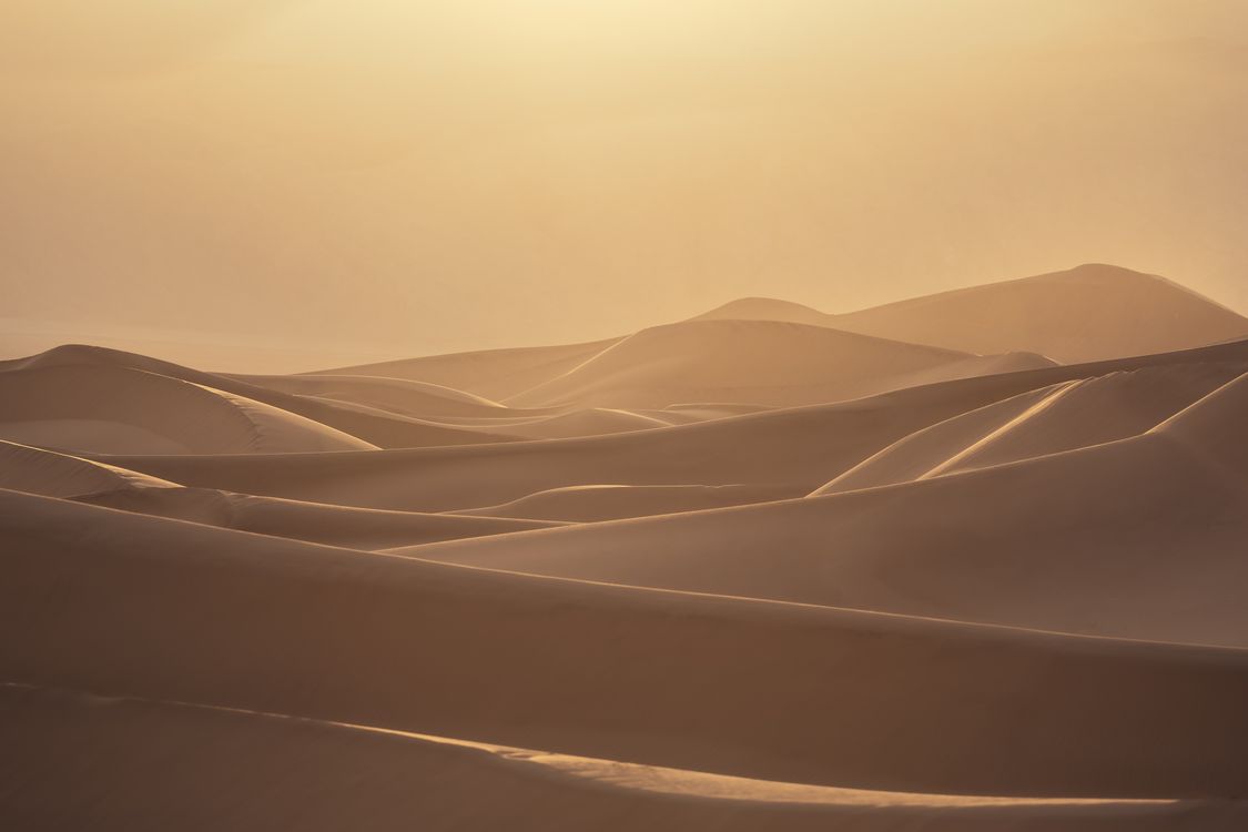 The sun is setting over the desert with sand dunes · Free Stock Photo