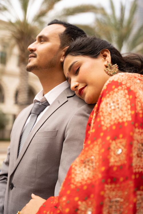 Free A couple lovingly embracing outdoors in elegant attire, capturing a moment of affection and style. Stock Photo