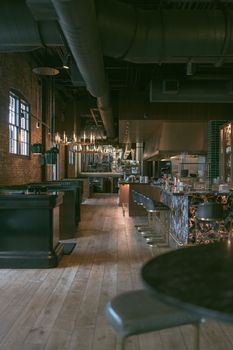 Modern industrial-style restaurant interior with wooden floors and elegant seating arrangements.