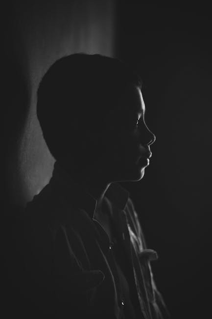 Captivating black and white portrait of a child in dramatic lighting, exuding mystery.