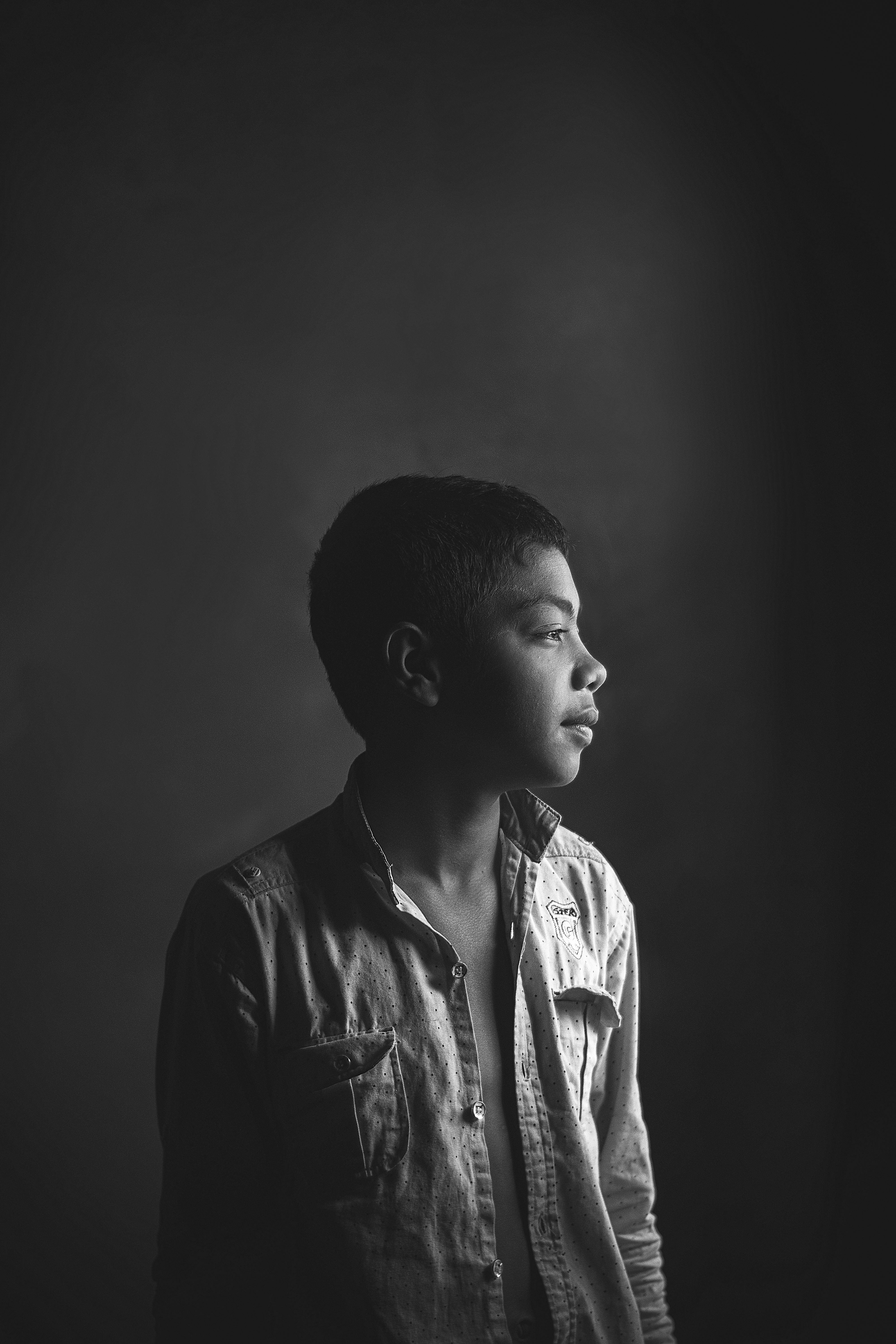 Captivating black and white profile portrait of a young boy with thoughtful expression.