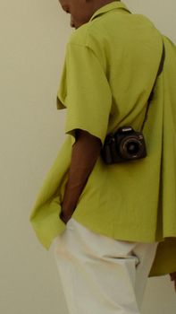 A person in a casual outfit with a camera, captured in a modern fashion style.