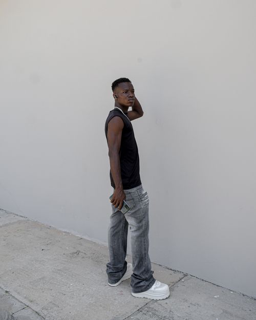 Free A fashionable young man in casual attire posing against a plain wall in urban Gabon. Stock Photo