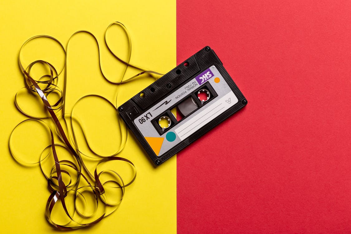 Black Cassette Tape on Top of Red and Yellow Surface