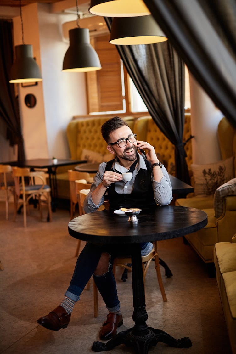 Photo Of An Elegant Man Drinking Coffee While Talking On The Phone