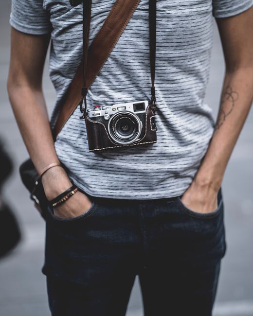 Stylish individual wearing a camera around neck, showcasing modern photography fashion.