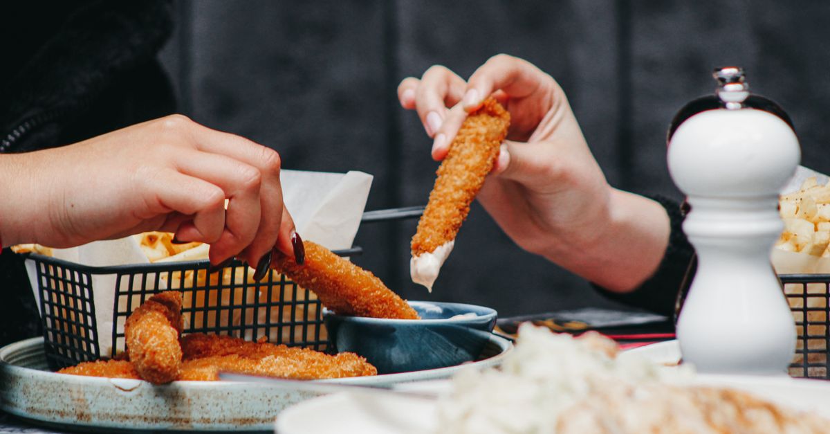 Apreciando dedos de frango crocantes com molho durante uma refeição compartilhada em um restaurante aconchegante.