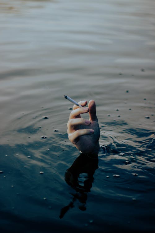 Hand with Cigarette Sticking Out of Water