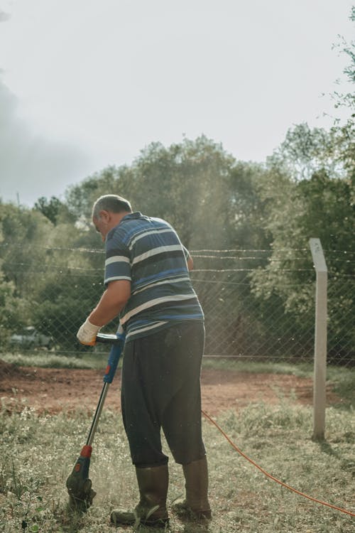 Man Mowing the Lawn with a Grass Trimmer 