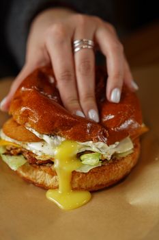 Deliciously cheesy and juicy burger held by a woman's hand, perfect for fast food lovers.