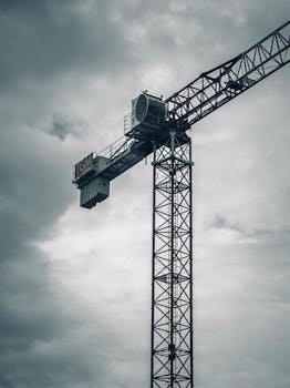 A towering construction crane silhouetted against an overcast sky, showcasing industrial power.