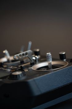 Close-up view of a remote controller device with a dark background showing metallic buttons and switches.