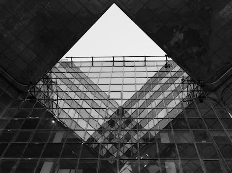 A striking black and white image of modern architecture in London, focusing on geometric glass structures.