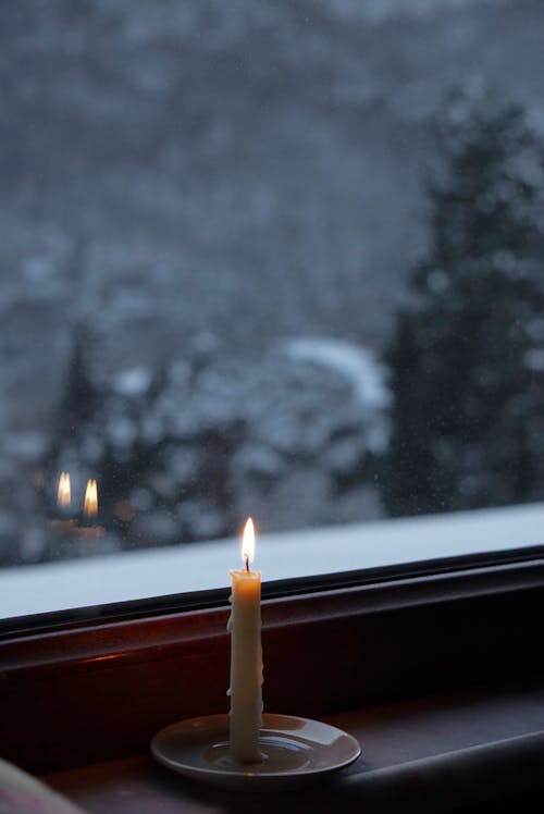 Wax Candle Burning on Windowsill