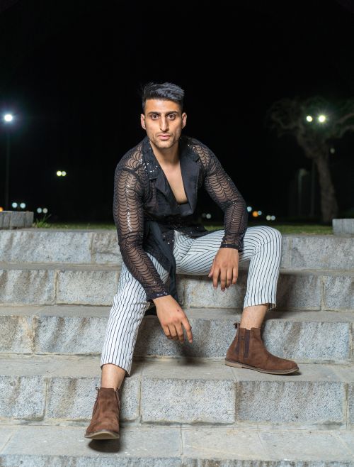 Free A fashionable man in black attire sitting on stairs at night, showcasing modern style. Stock Photo