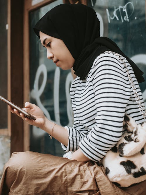 Woman in Hijab Sitting with Cellphone