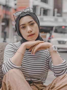 Stylish young woman wearing hijab and sunglasses in urban setting.